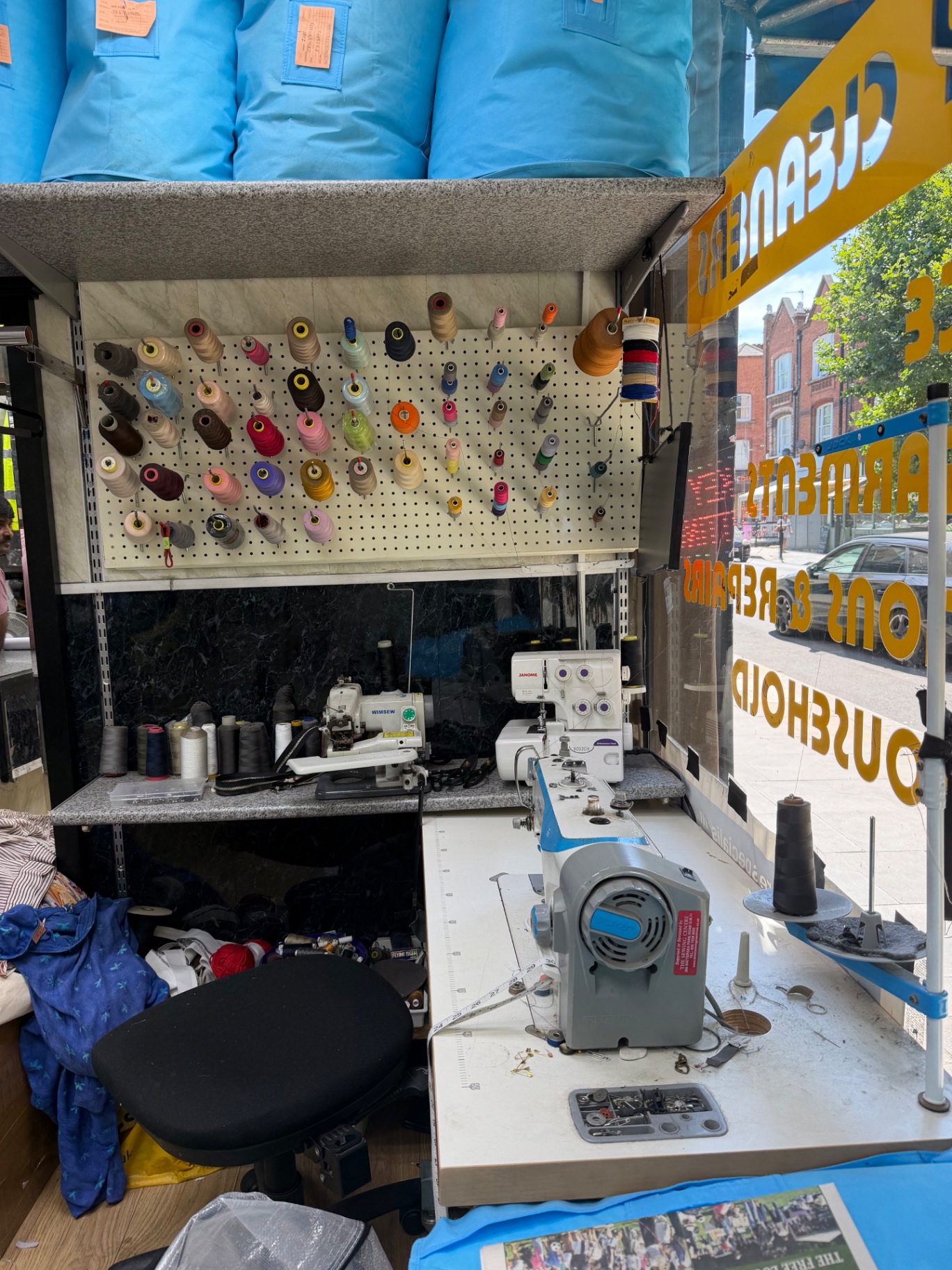 Sewing and alterations station with a wall of coloured threads