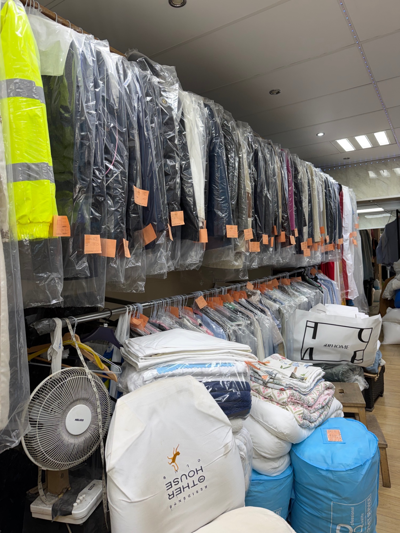 Racks of freshly cleaned garments in plastic covers with orange tags